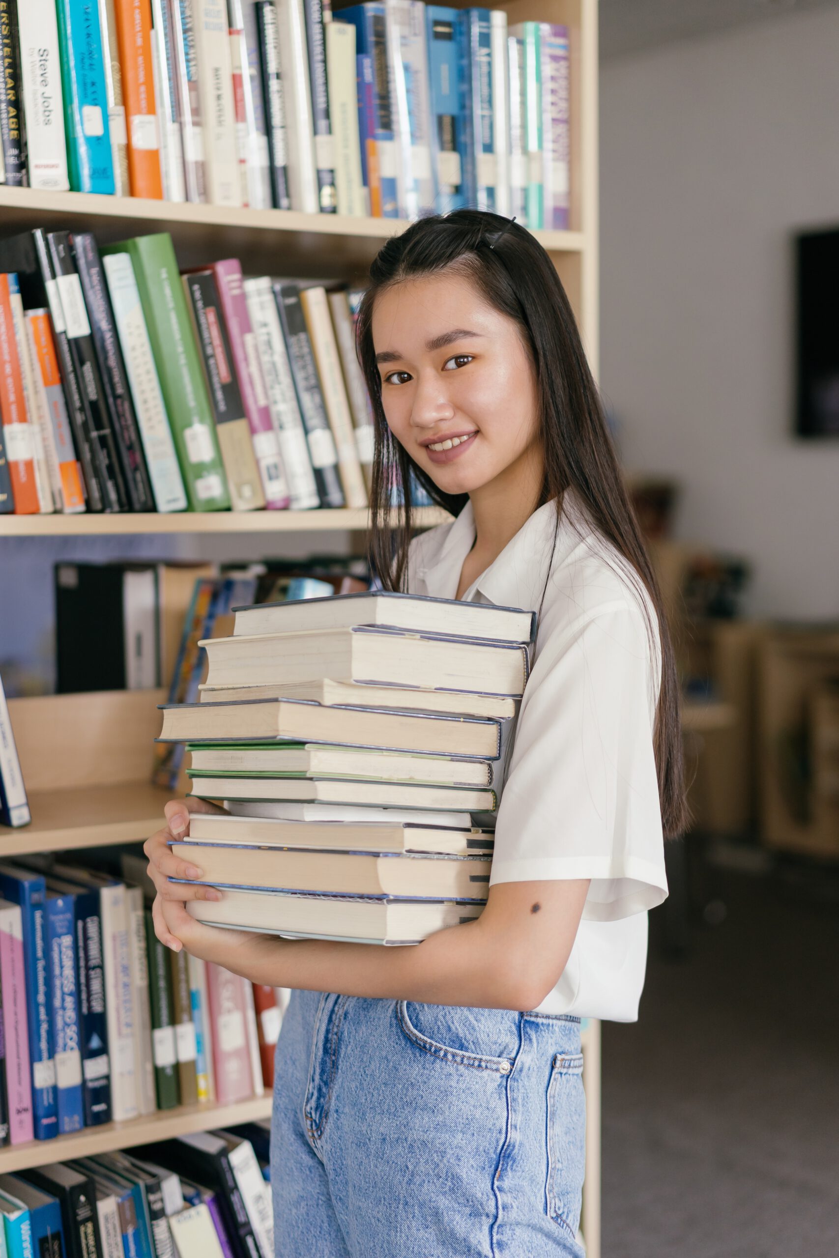 Meisje draagt een stapel boeken.